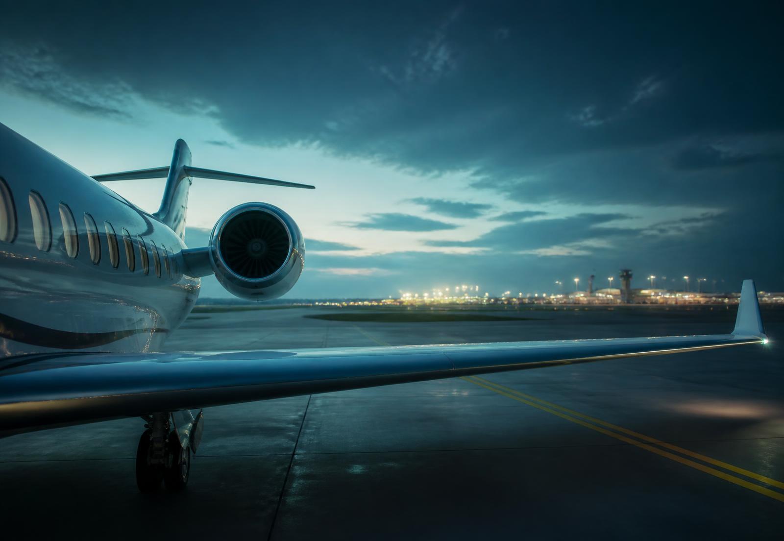 Business jet wing and engine on a quiet ramp at blue hour