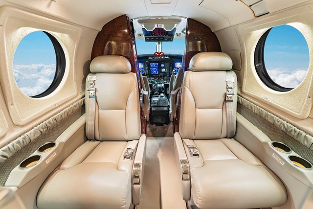 Light jet cabin looking forward to the flight deck with cream leather seating
