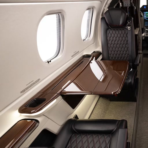 Quilted leather cabin seating and polished wood folding table inside a light business jet