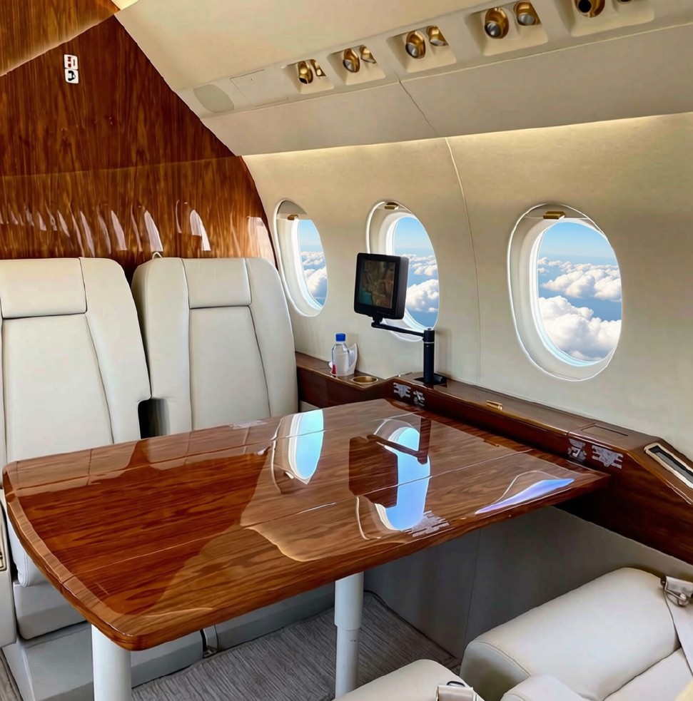 Large-cabin jet interior with polished wood conference table above the clouds