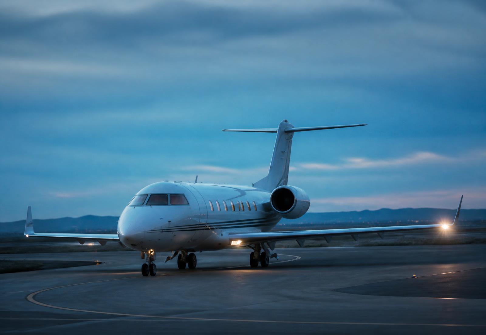 Midsize business jet taxiing at dusk with landing lights on